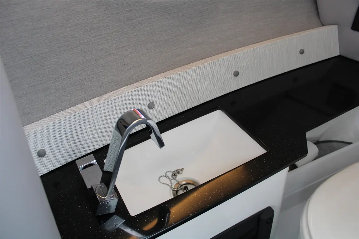 Modern black countertop with a sleek chrome mixer tap over a white sink, set against a textured grey wall.